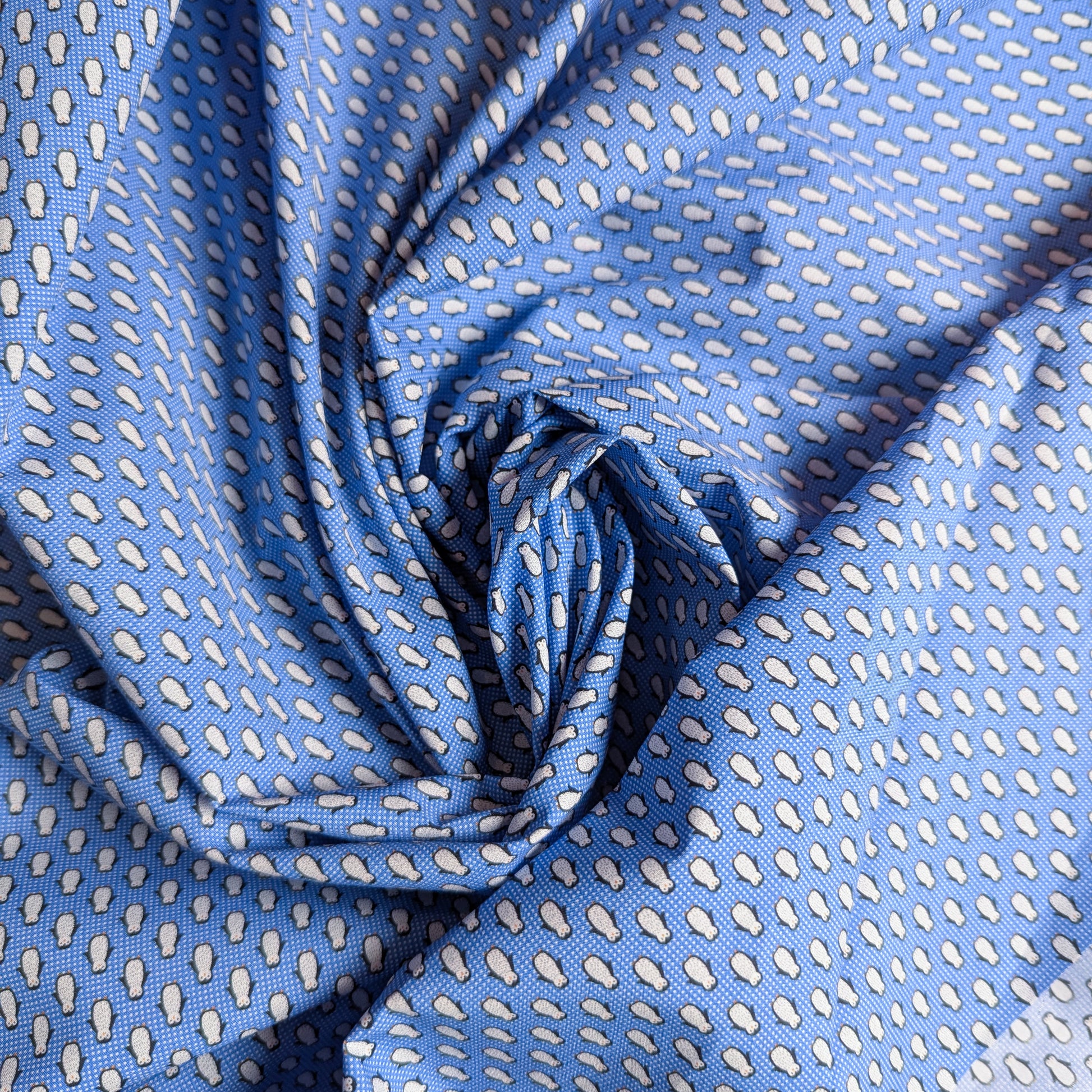 Blue cotton poplin deadstock fabric with a white teardrop pattern, draped in soft folds.