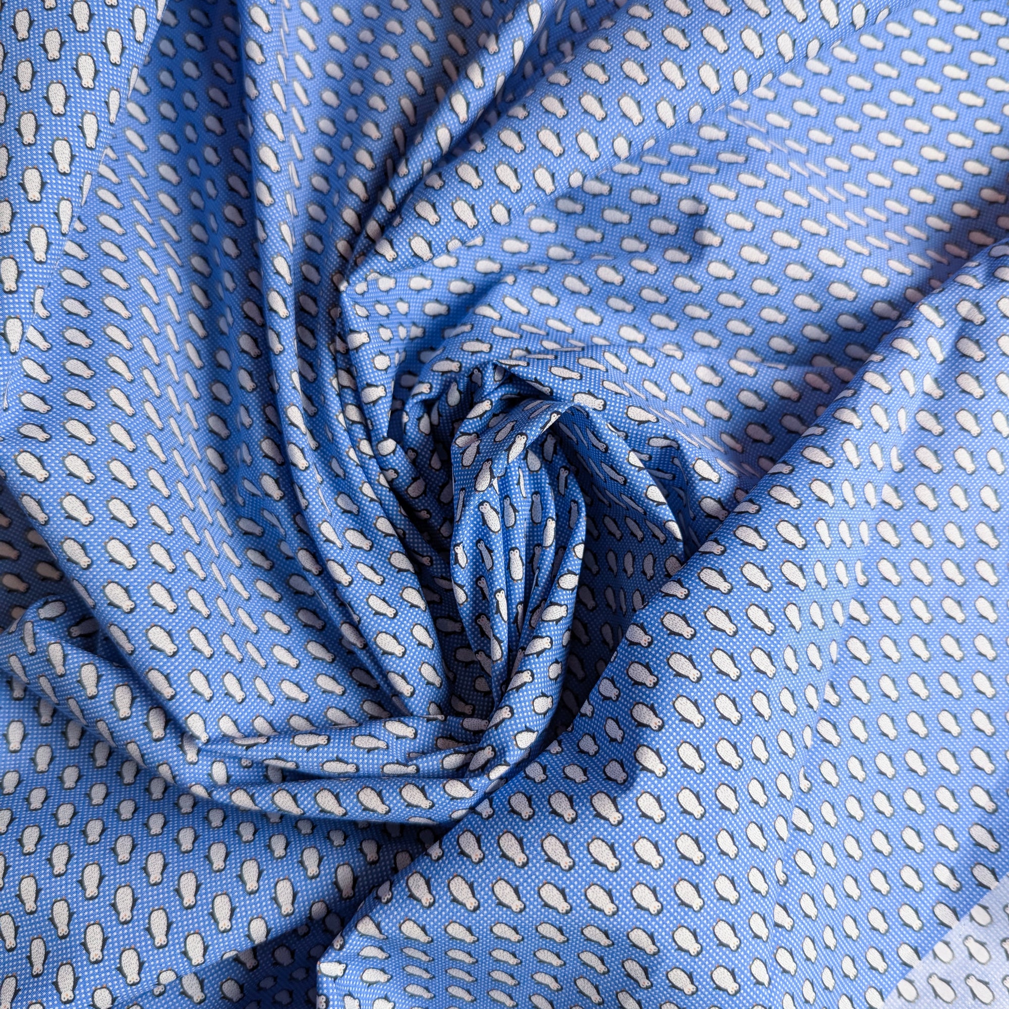 Pantone blue deadstock cotton poplin fabric with a white penguin pattern, 140 cm wide.