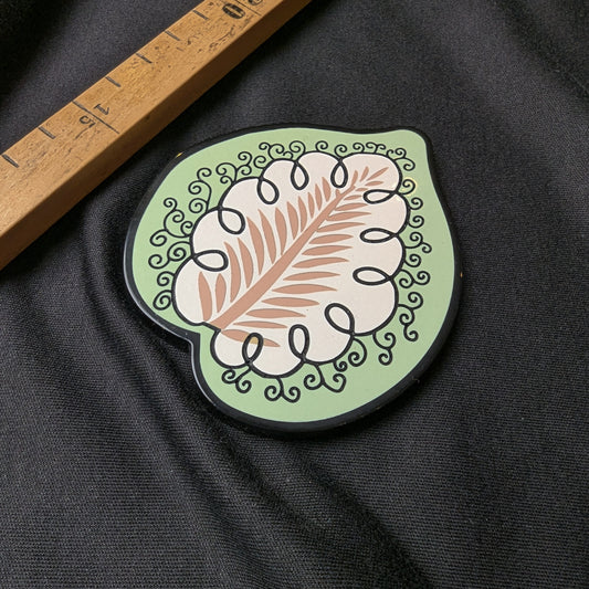 D&G plastic patch with light green border, white cloud-like shape, brown leaf design, and black swirls.