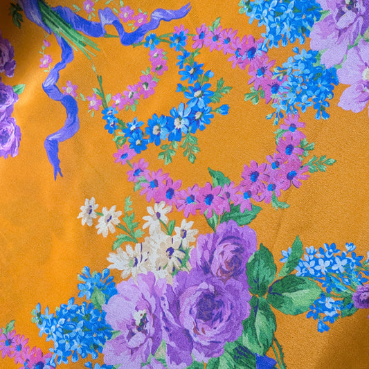 Dark cheddar silk crêpe de Chine fabric with vibrant purple and blue floral print.