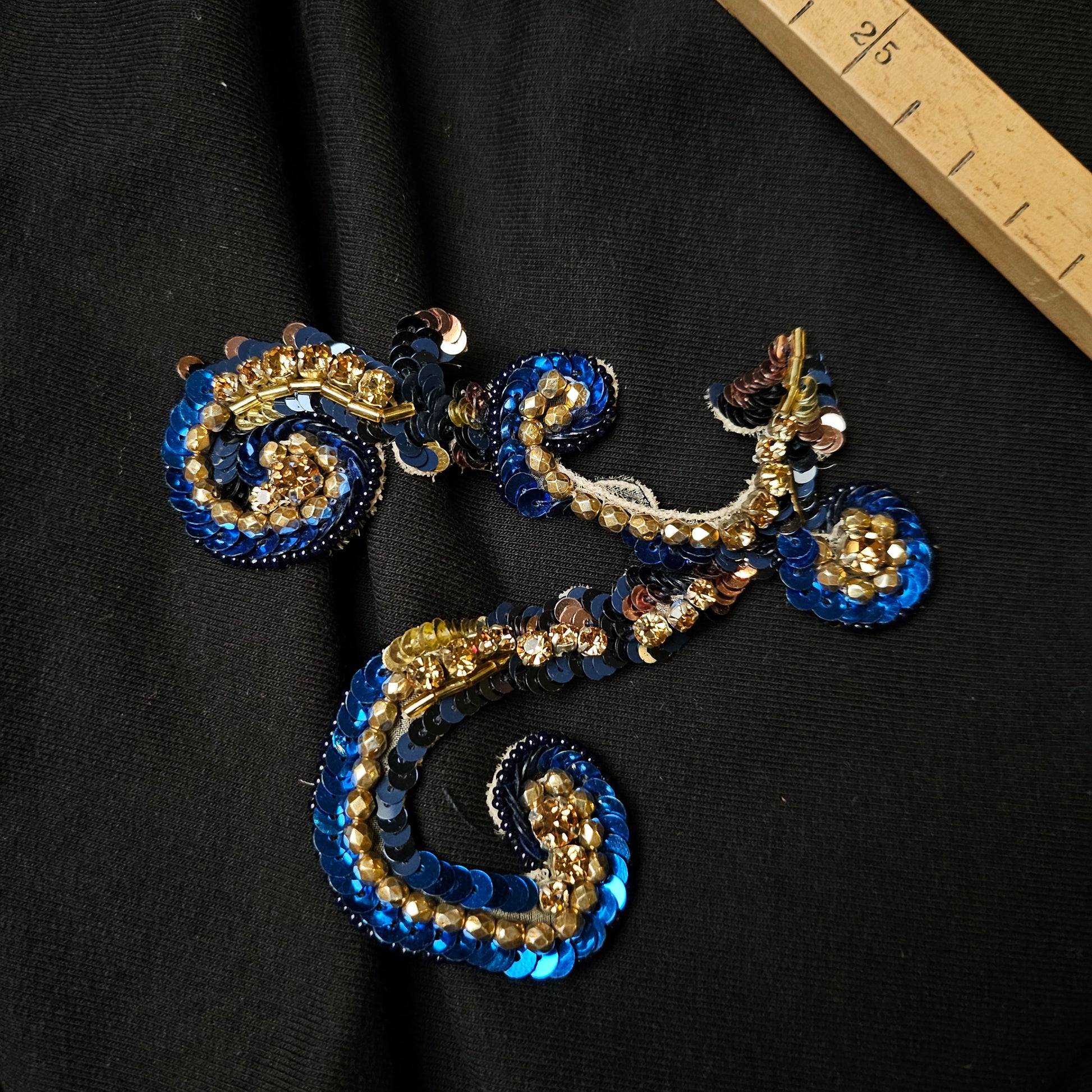 Dolce & Gabbana blue and gold sequin ornamental patch, 10 cm, on black fabric.
