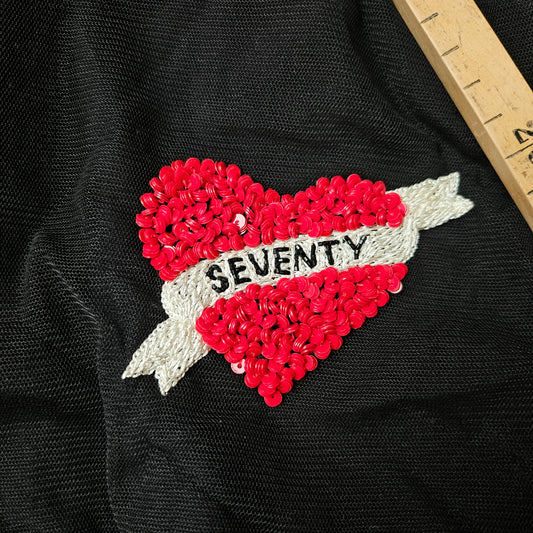 Red sequin heart patch with "SEVENTY" on a white banner, on black fabric.