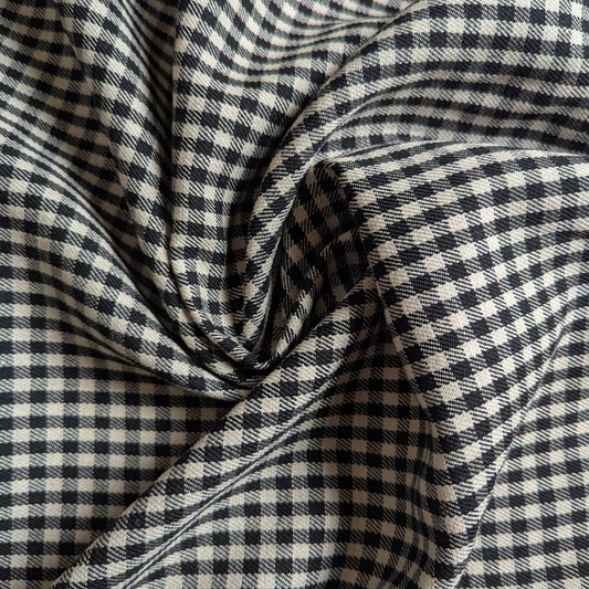 Black and white gingham wool fabric, textured with a small check pattern, draped in soft folds.