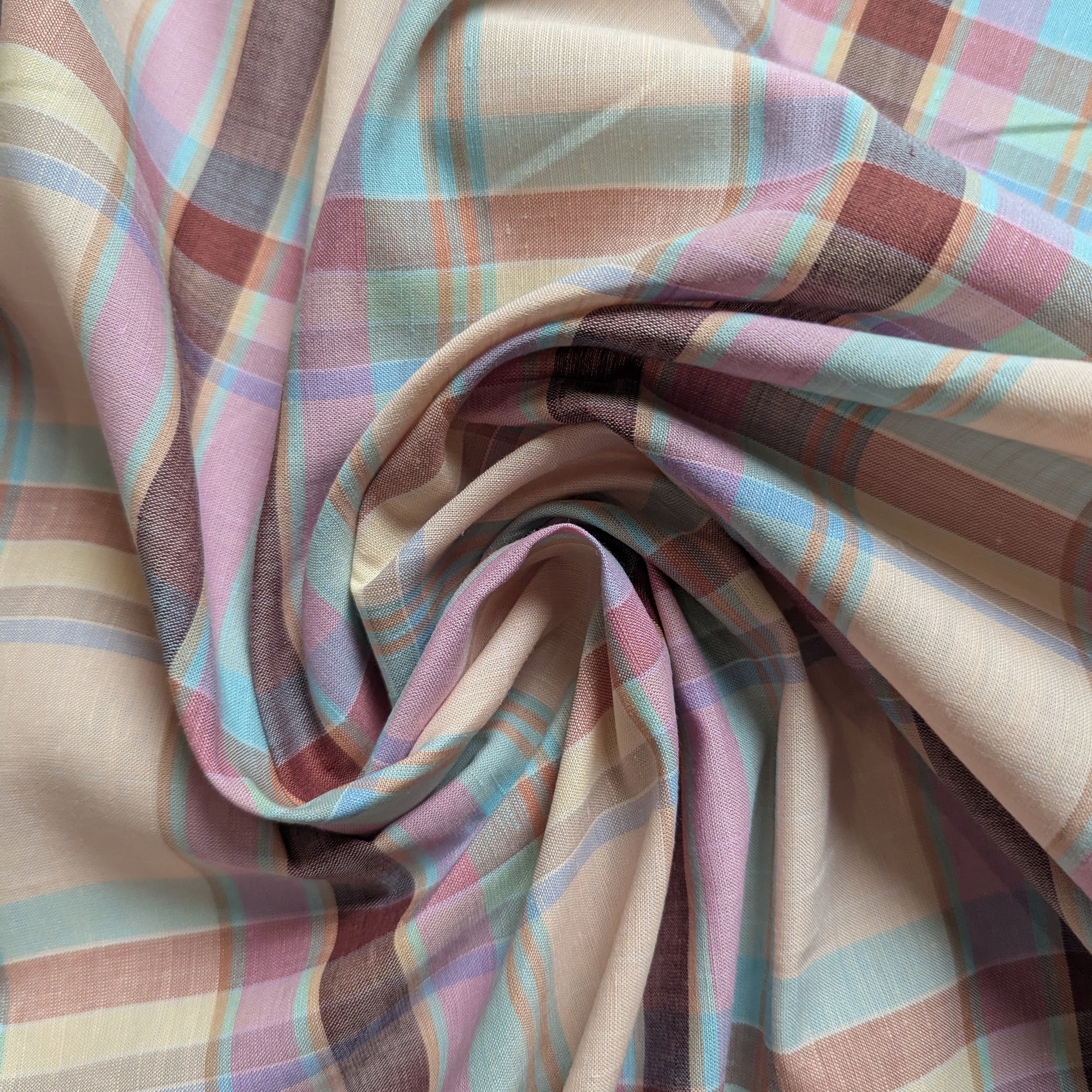 G*cci deadstock cotton-linen fabric with muted pastel tartan pattern in pink, blue, and beige tones.