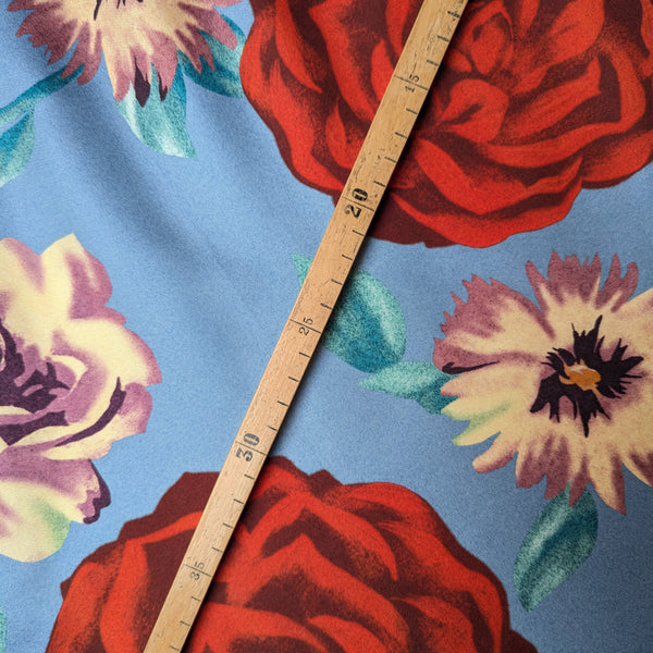 Light blue Ferragamo deadstock silk twill fabric with large red and cream floral print, measured by a wooden ruler.
