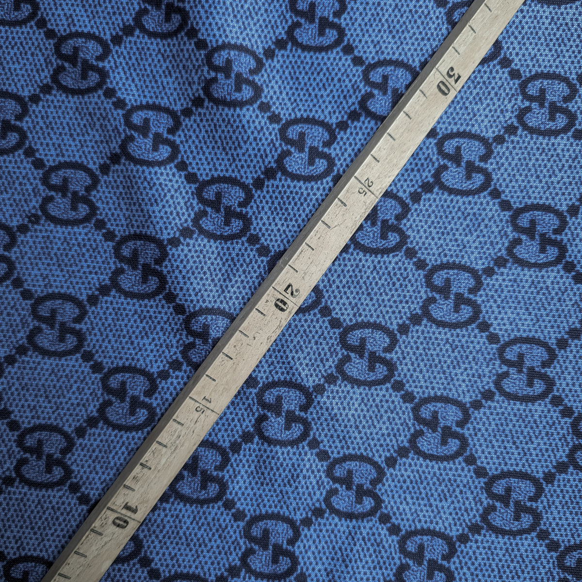 Blue Punto Milano deadstock fabric with black G*cci monogram pattern and a measuring stick.