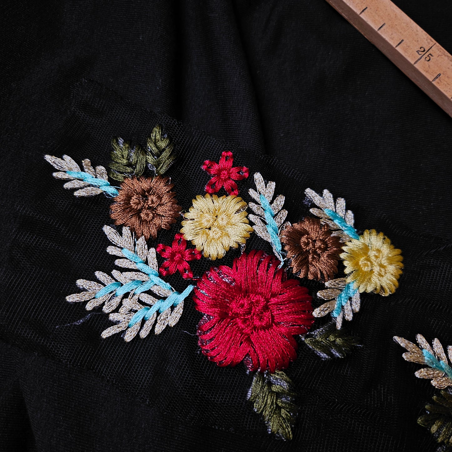 D&G floral embroidery patch on black fabric, featuring colorful red, yellow, and brown flowers with blue and green leaves.