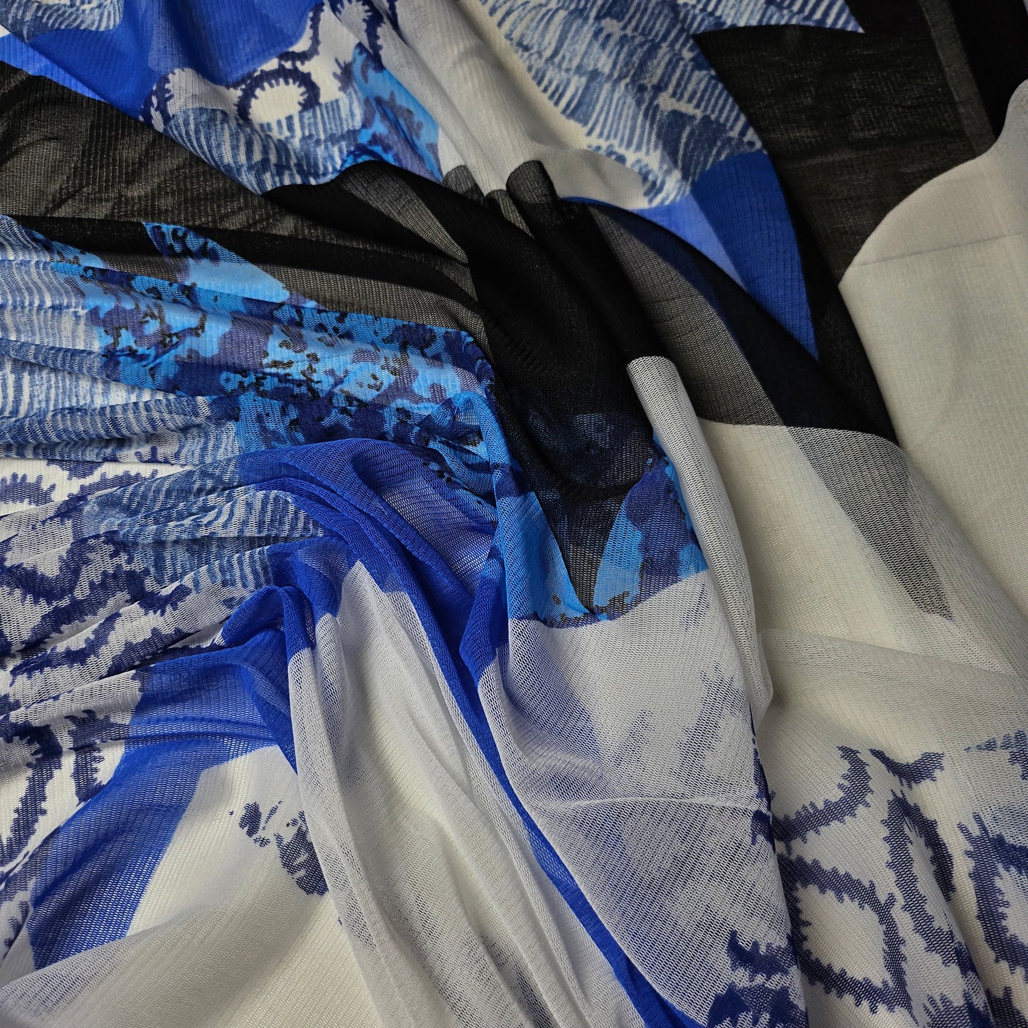 Deadstock fine tulle fabric, 185cm wide, with abstract blue, black, and white print.