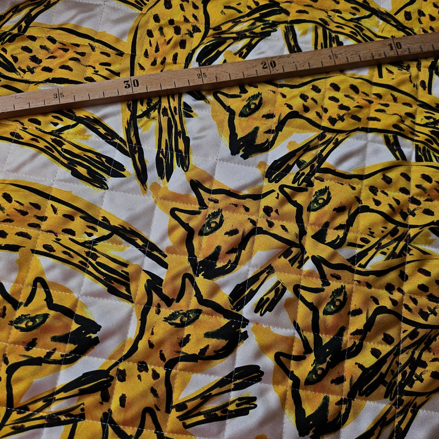 AZ-Factory deadstock quilted fabric with yellow & black stylized cat print, green eyes, and ruler for scale.