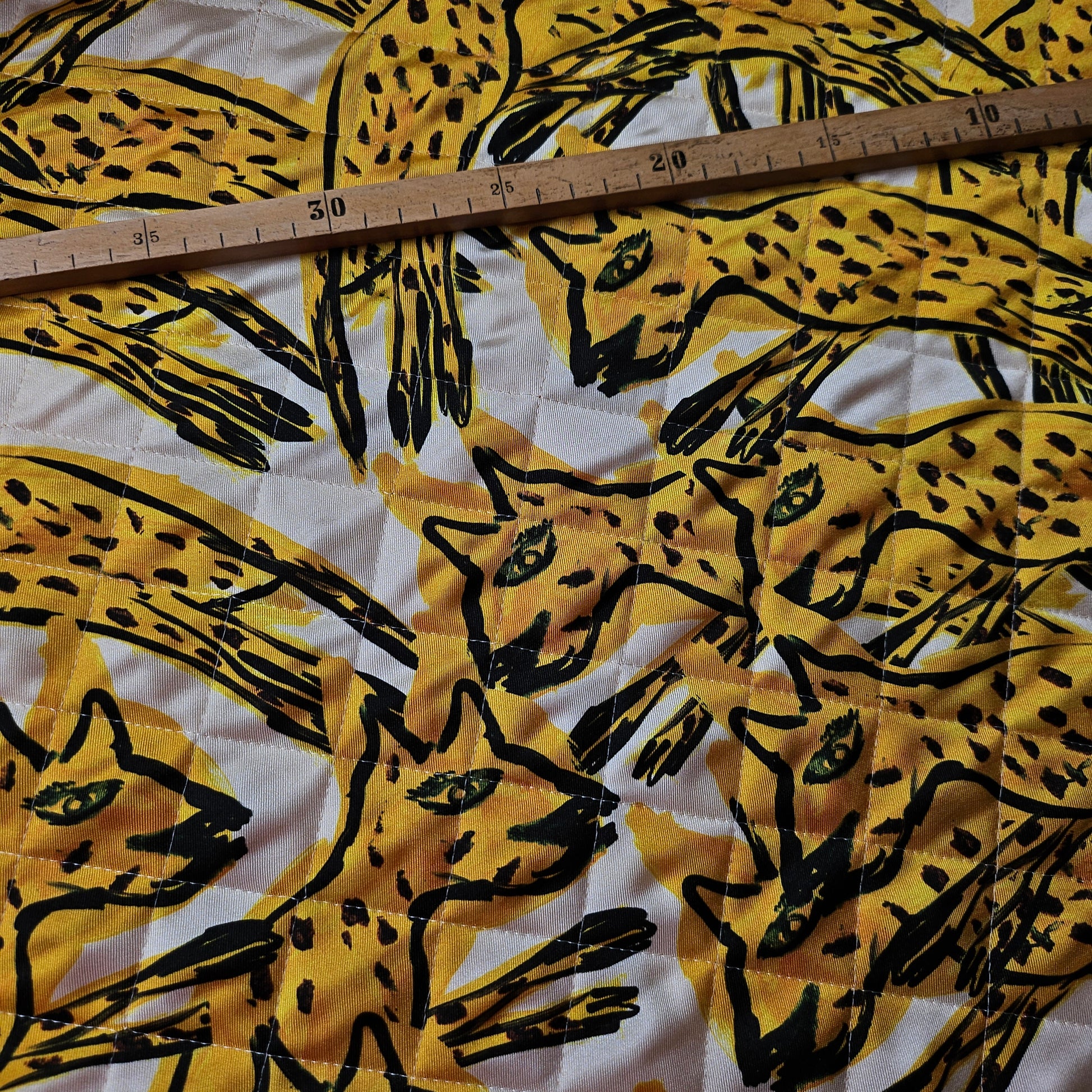 AZ-Factory deadstock quilted fabric with yellow & black stylized cat print, green eyes, and ruler for scale.
