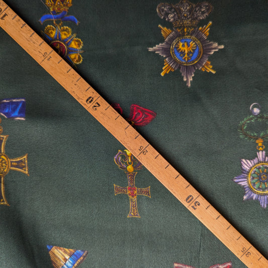 British Green D&G deadstock viscose twill fabric with colorful ornate medal patterns and a wooden ruler.