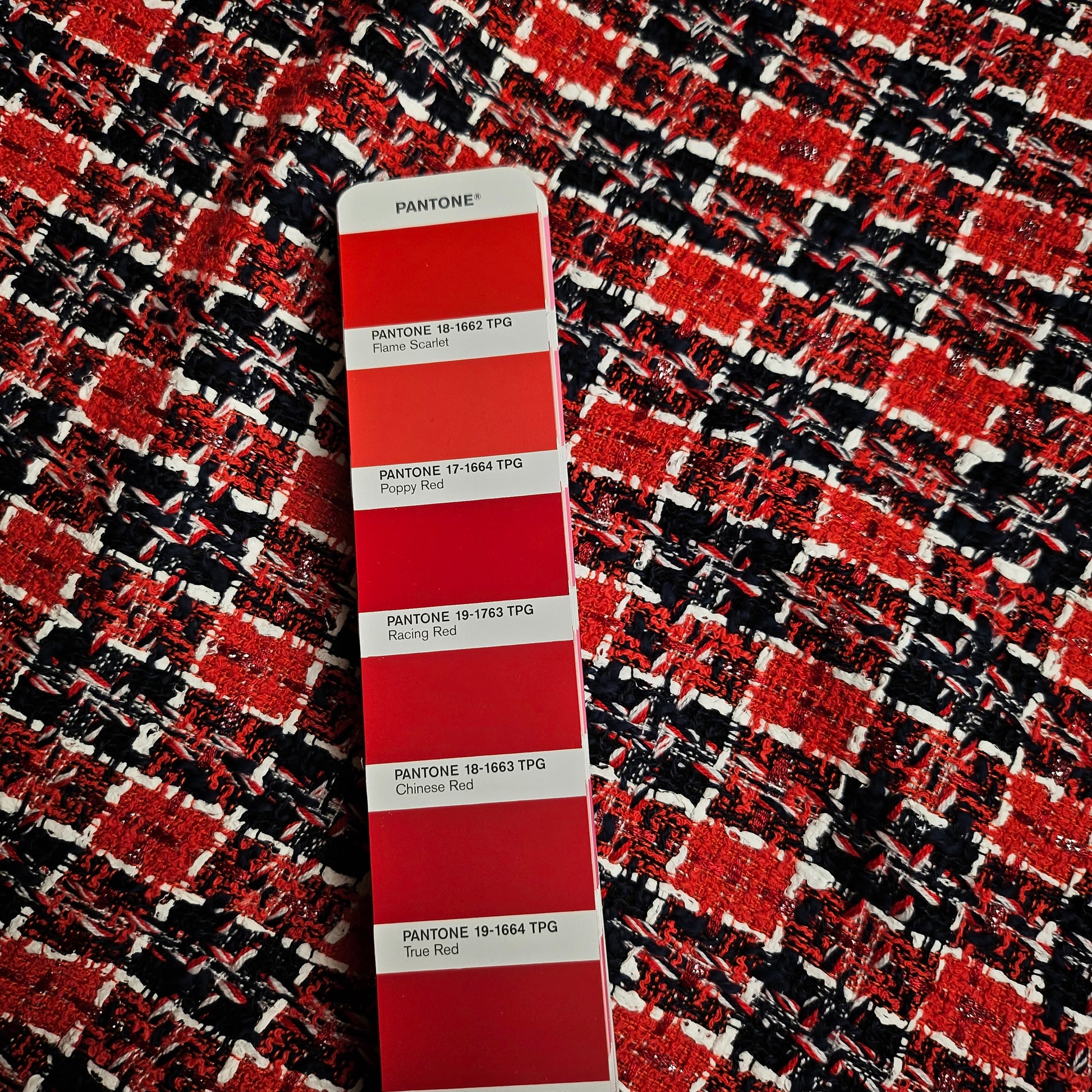 Red, black, and white tweed fabric with a Pantone color swatch showing various red shades.