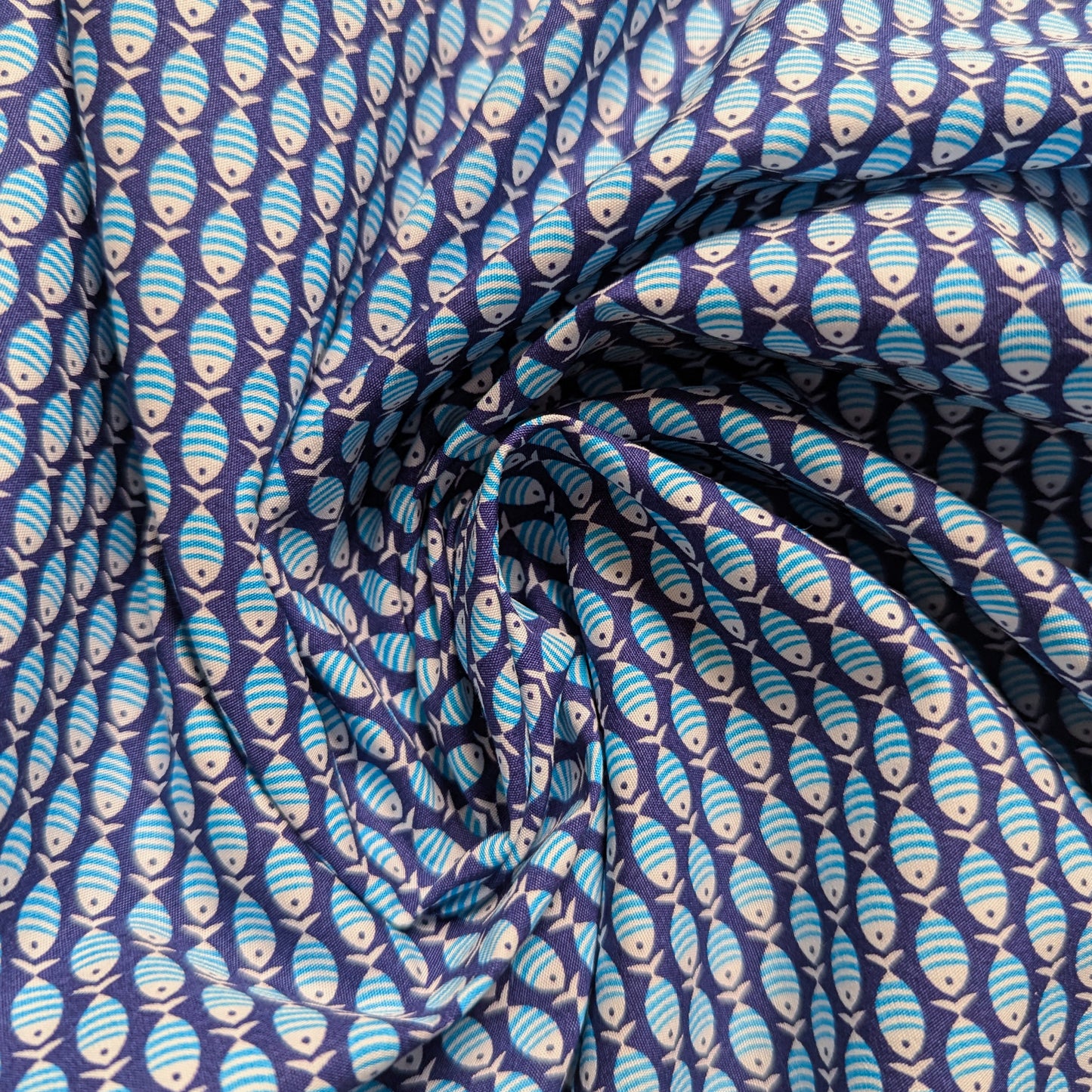 Deadstock dark blue cotton poplin fabric, 140cm wide, with a repeating light blue and white fish pattern.