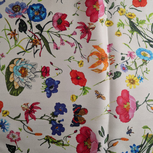White deadstock silk twill fabric with a vibrant, colorful garden floral print.