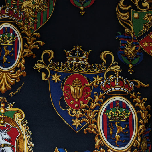 D&G black cotton twill fabric with elaborate gold, red, and blue crests, crowns, and mythical creatures.